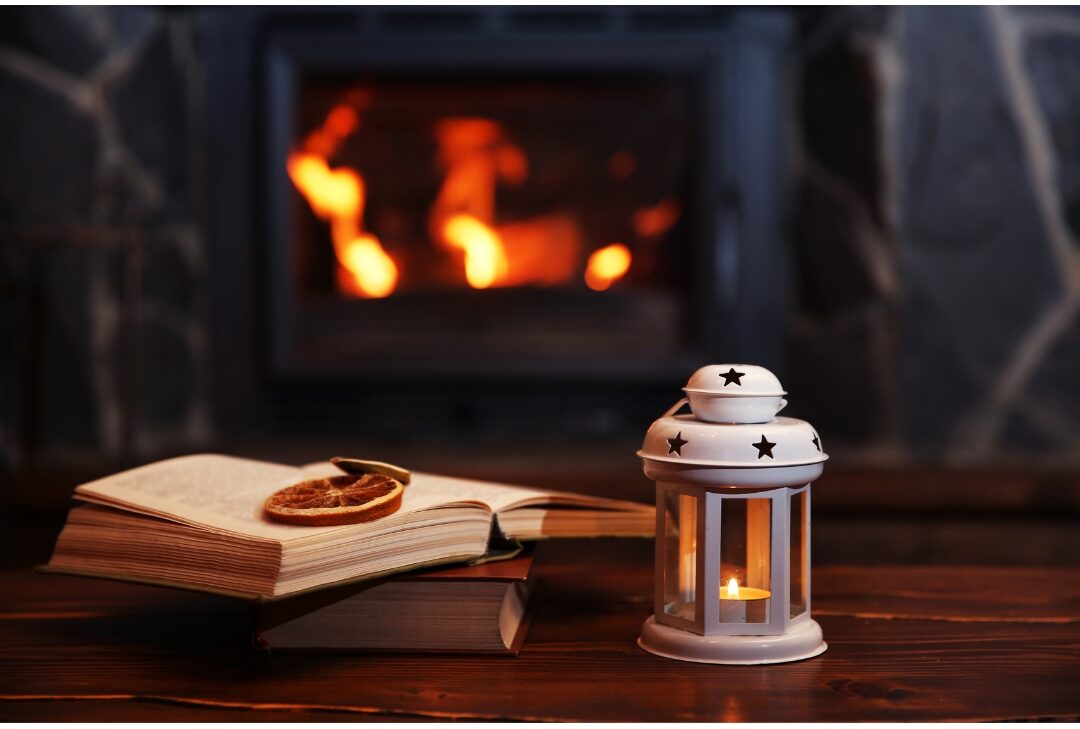 flickering LED candles inside clear glass lanterns on wooden fireplace hearth