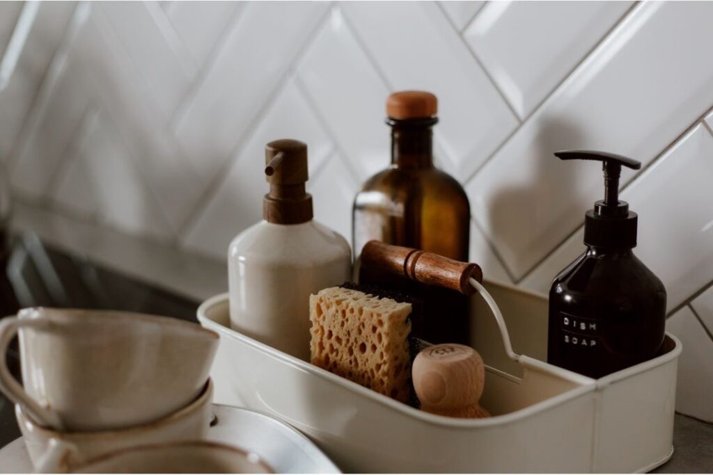 amber glass soap dispenser sitting neatly beside ceramic kitchen sink