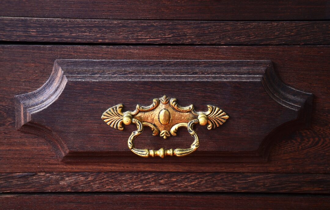 close up of brushed brass drawer pull handle on dark wood cabinet