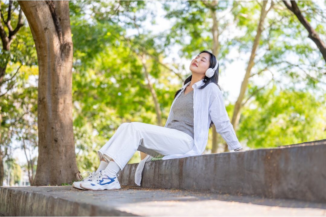 woman leaning back calmly on outdoor bench looking peaceful