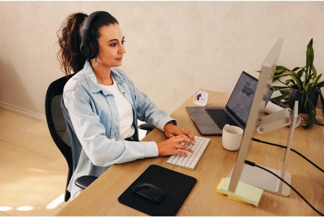 focused woman wearing headphones working peacefully at closed office door desk managing the biggest distractions in every home office