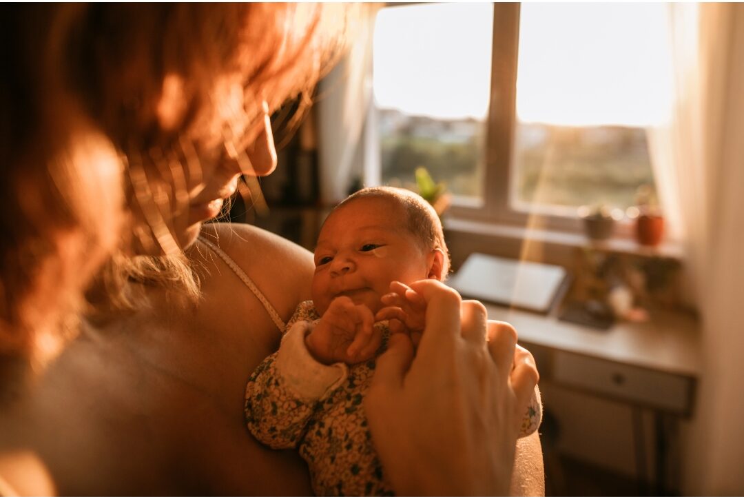 mother holding young toddler gently in warm morning sunlight honoring her current life season