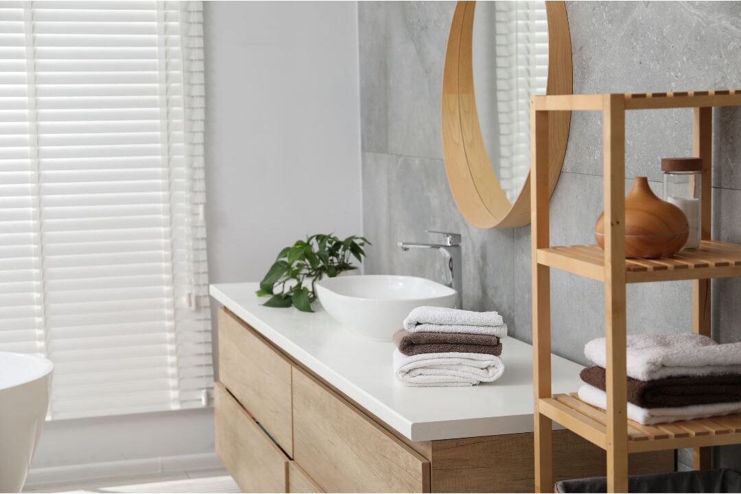 clean white bathroom vanity with small vase and folded towel