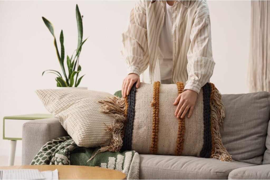 neatly arranged living room couch with fluffed neutral pillows displaying the home reset trick that changed my entire week
