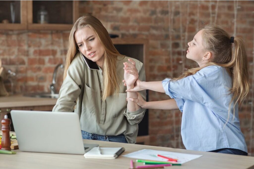 mother attempting to work on laptop while child asks for attention presenting nobody talks about this reason moms feel exhausted