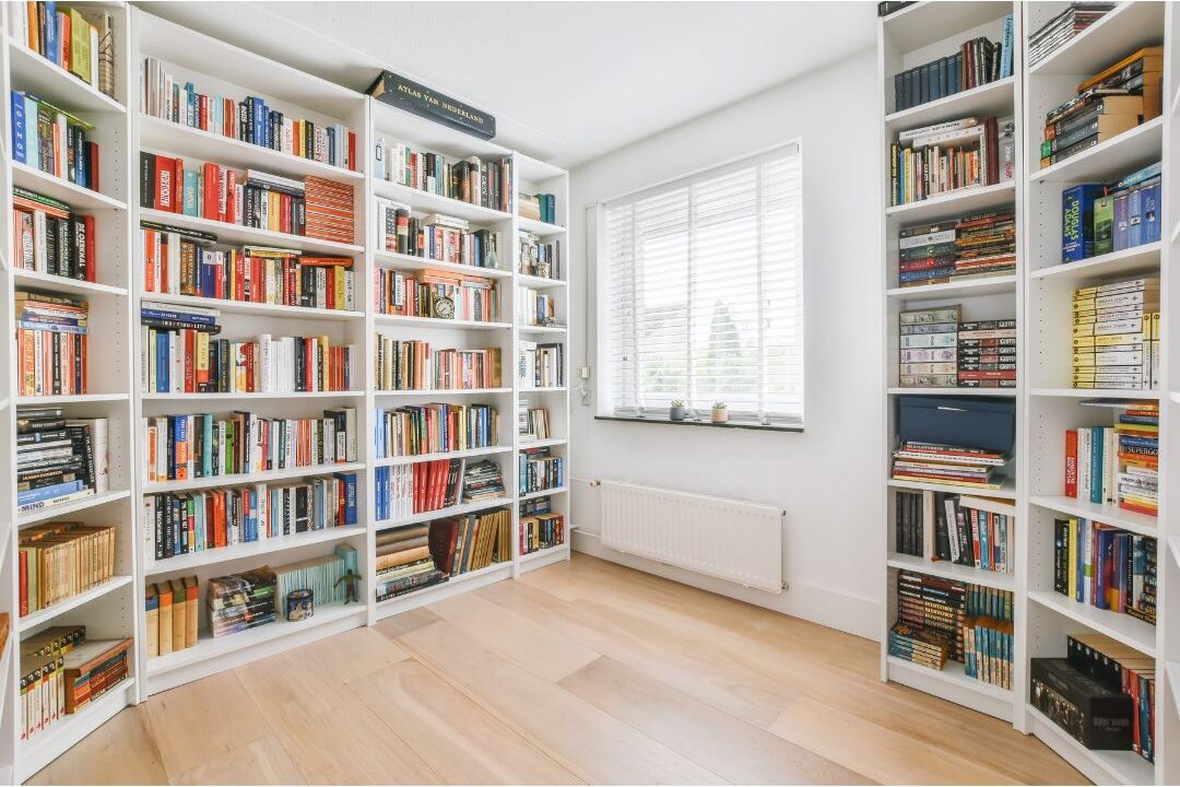 sunlit home library study filled with floor to ceiling book shelves