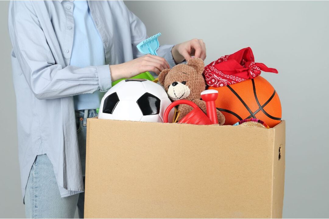 hand placing unwanted items into cardboard donation box presenting I stopped doing these 12 things my home has never been cleaner