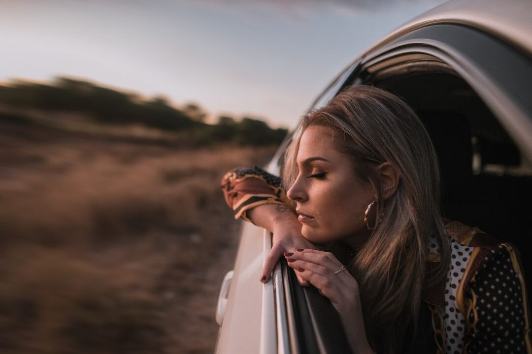 woman sitting calmly in car with eyes closed taking deep breath