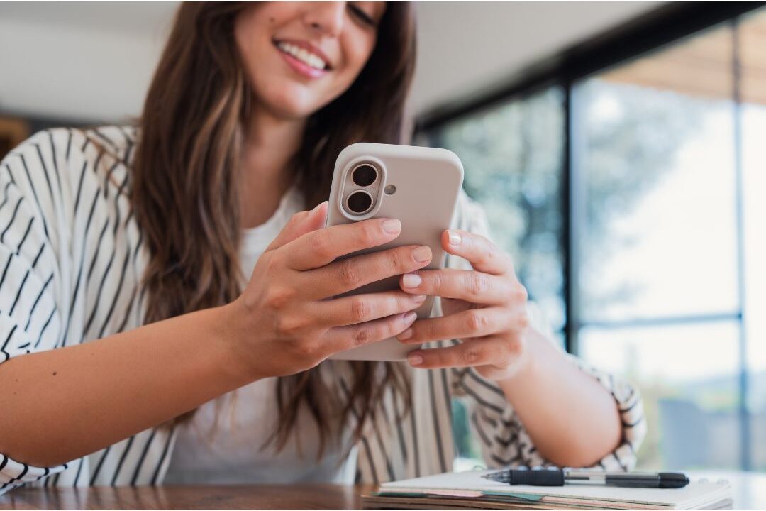 woman typing note on mobile screen in clean modern kitchen