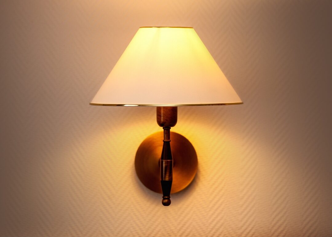 minimalist brass wall sconce casting warm light down onto soft armchair highlighting 40 cozy home ideas you'll want to copy