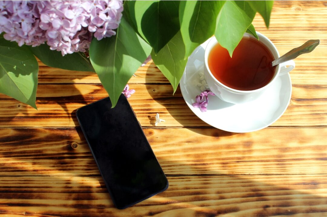 smartphone turned face down on wooden coffee table beside cup of herbal tea breaking comparison trap