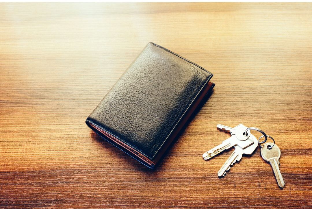 wooden entryway bench holding brass keys and small leather wallet