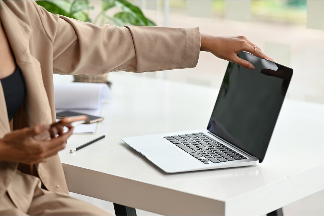 woman closing laptop peacefully on clean wooden desk knowing you're not lazy you're probably overloaded