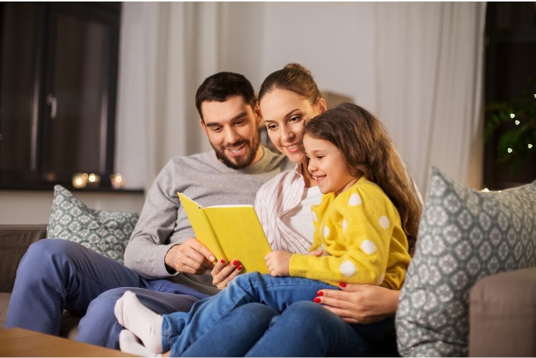 family sitting together on large sofa reading individual physical books silently presenting 25 family traditions worth starting