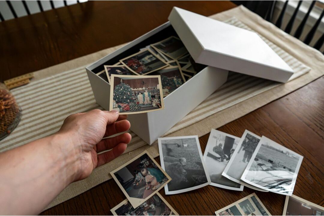 family packing wooden box with photos, notes, and small objects on carpet
