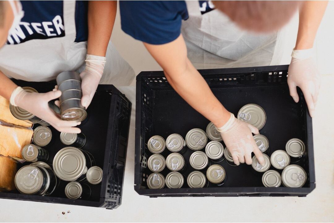 family sorting canned food donation boxes at community food bank featuring 25 family traditions worth starting