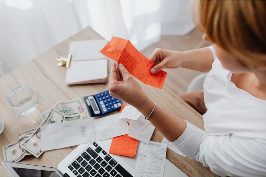 woman sorting bills and school papers at clean wooden desk