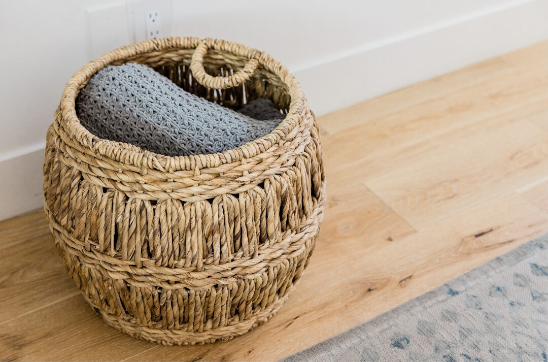neatly folded woven throw blanket sitting in a wicker storage basket