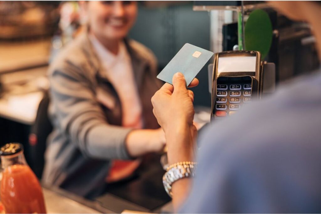 mother tapping payment card showing money habits that keep families broke