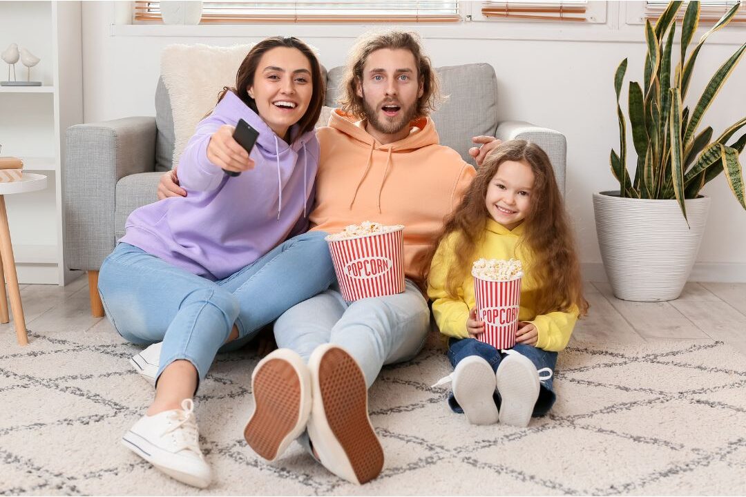 family eating homemade pizza on living room floor watching movie together showcasing 25 family traditions worth starting