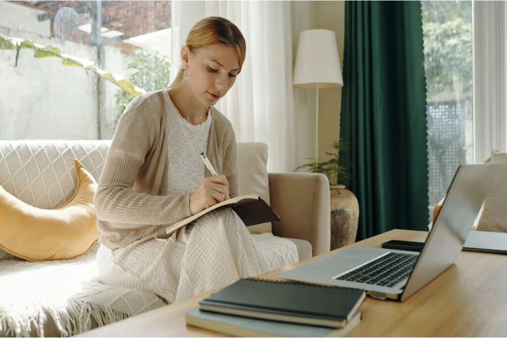 woman taking notes at desk to lower household service bills