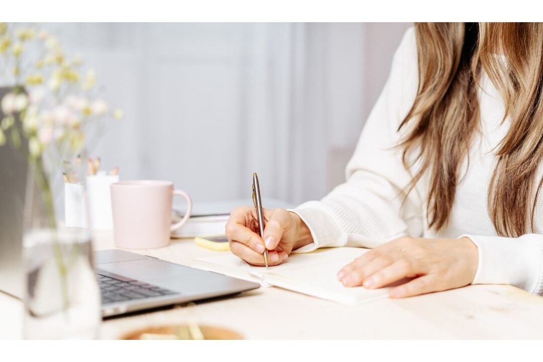woman sitting calmly at wooden table writing thoughtfully