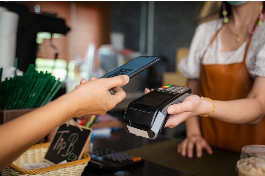 person paying for coffee with smartphone showing micro transactions if you never have money left over read this
