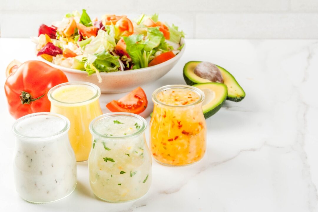 glass jar filled with homemade olive oil salad dressing identifying 50 things to stop buying to save money