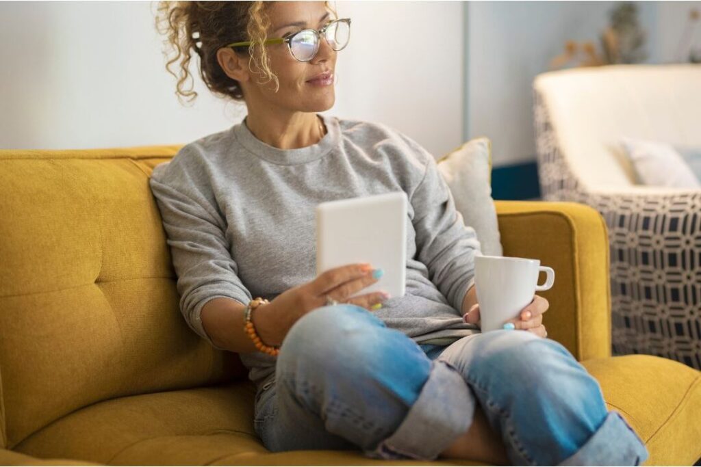 mother sitting calmly with coffee tablet illustrating how to save money even if you're living paycheck to paycheck
