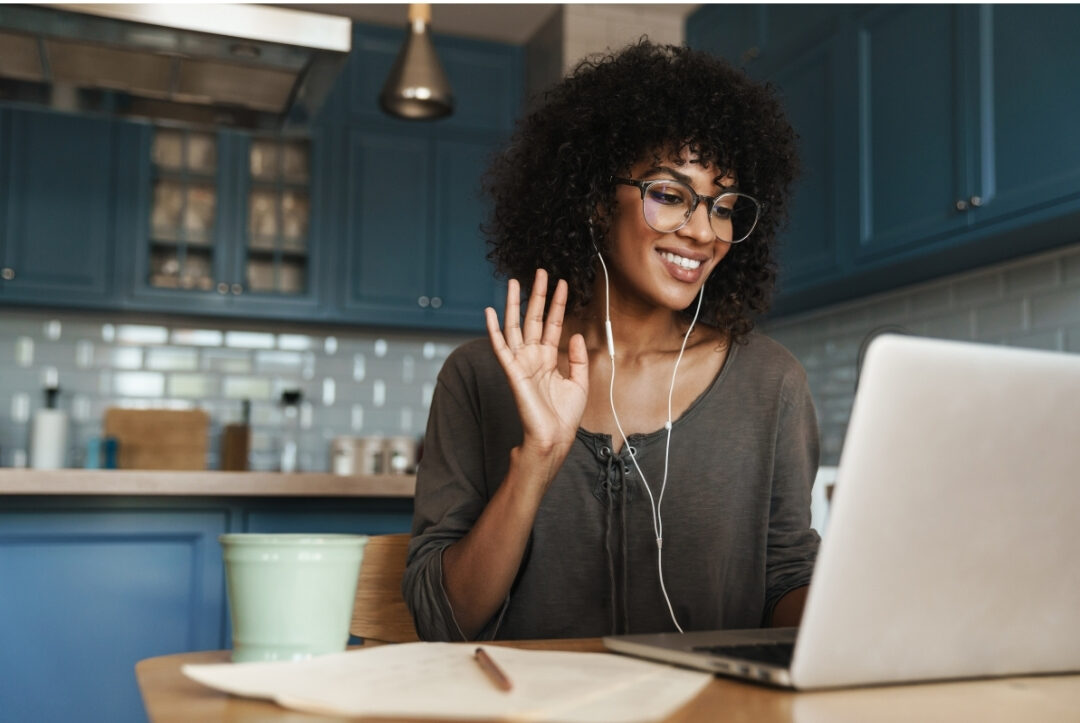 woman smiling during warm video co working call on laptop at desk maintaining social connection