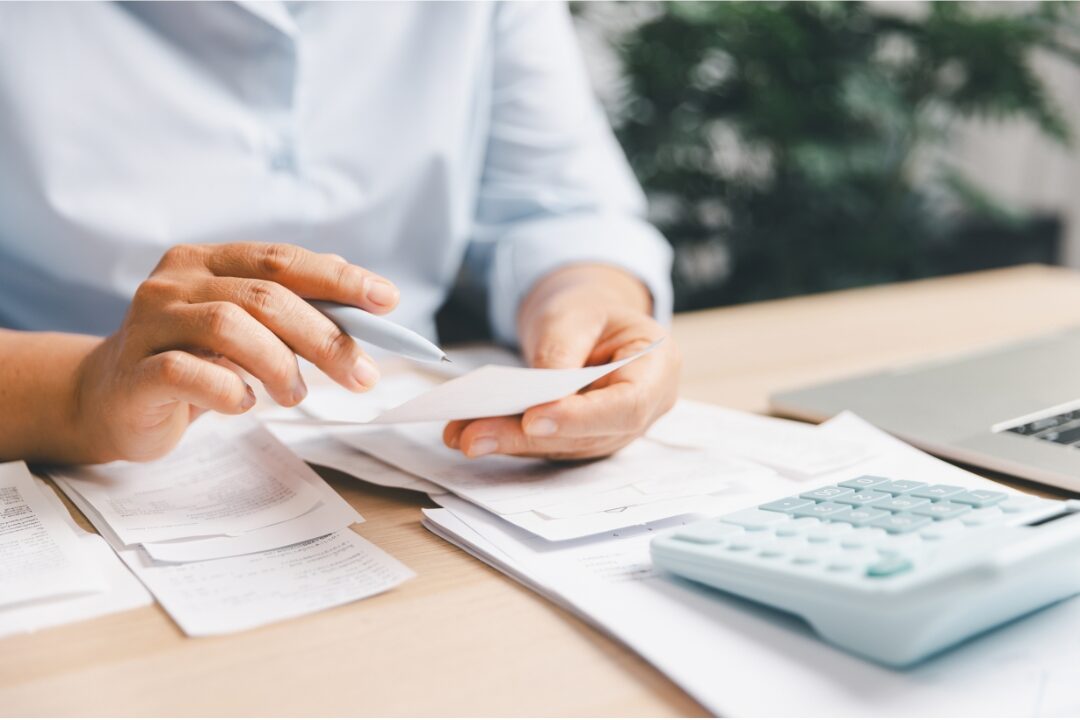 clip board holding financial budget tracking sheet beside wall calendar organizing family finances