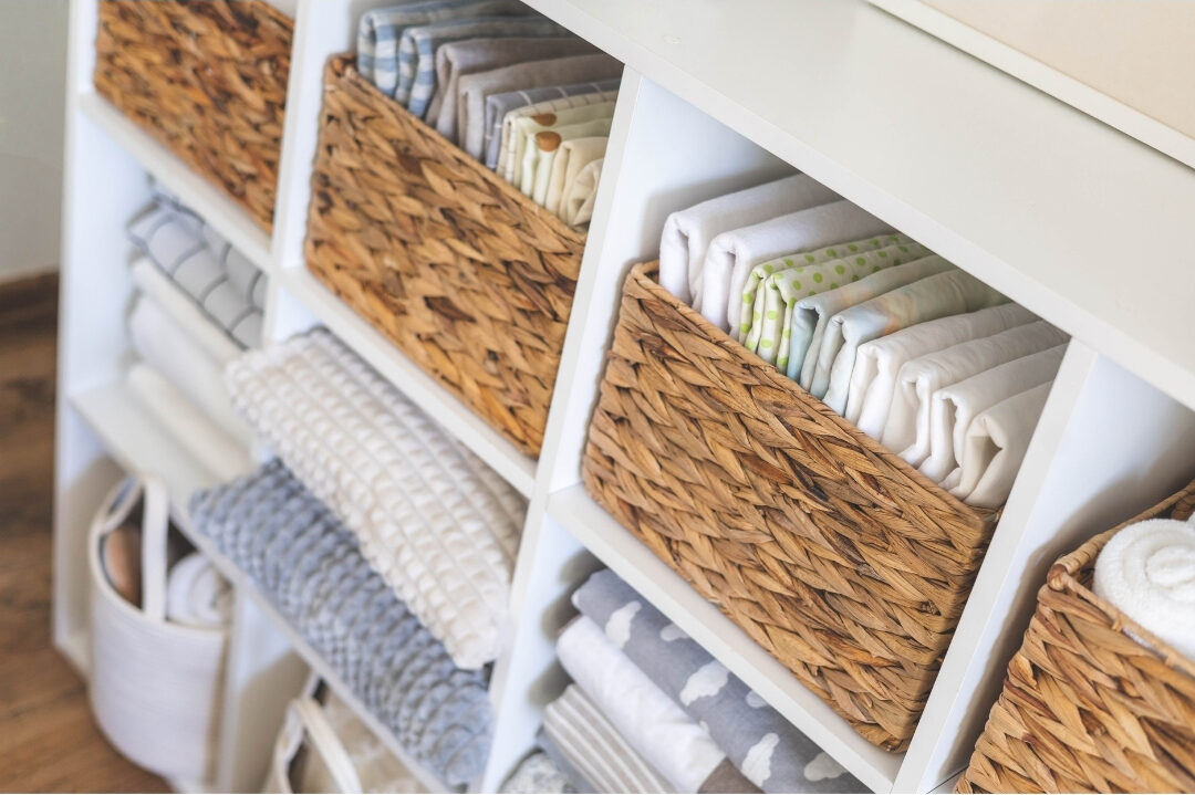 neatly organized linen closet filled with folded white sheets and baskets