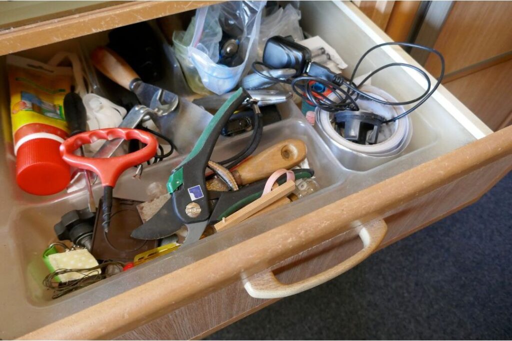 open shelf gap stuffed with random tools batteries and rubber bands displaying the one shelf that makes every house look messy