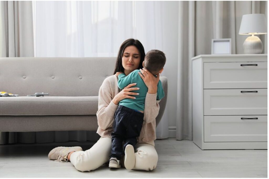 mother comforting upset toddler gently on living room floor
