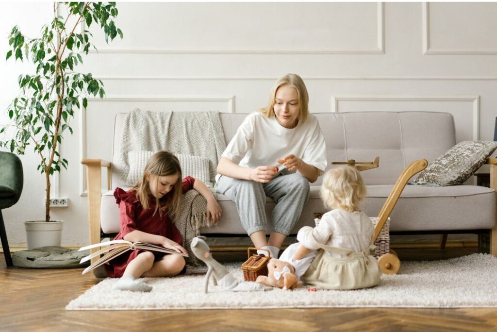 mother watching young children playing in living room attentively revealing nobody talks about this reason moms feel exhausted