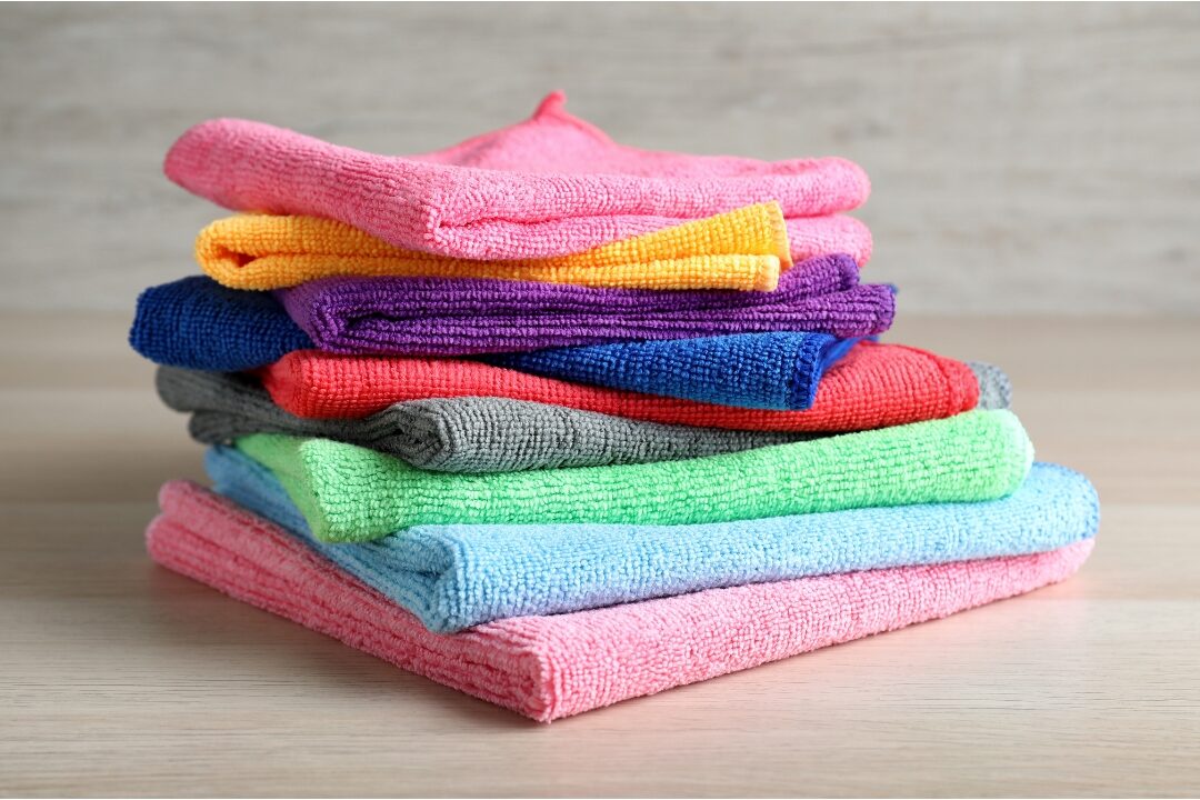 stack of folded colorful microfiber cleaning cloths demonstrating 50 things to stop buying to save money