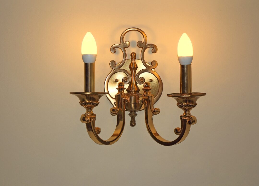 minimalist brass wall sconce illuminating a textured plaster wall