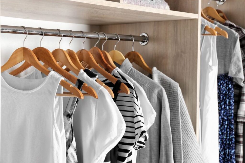 organized bedroom closet with uniform wooden hangers and organized clothes