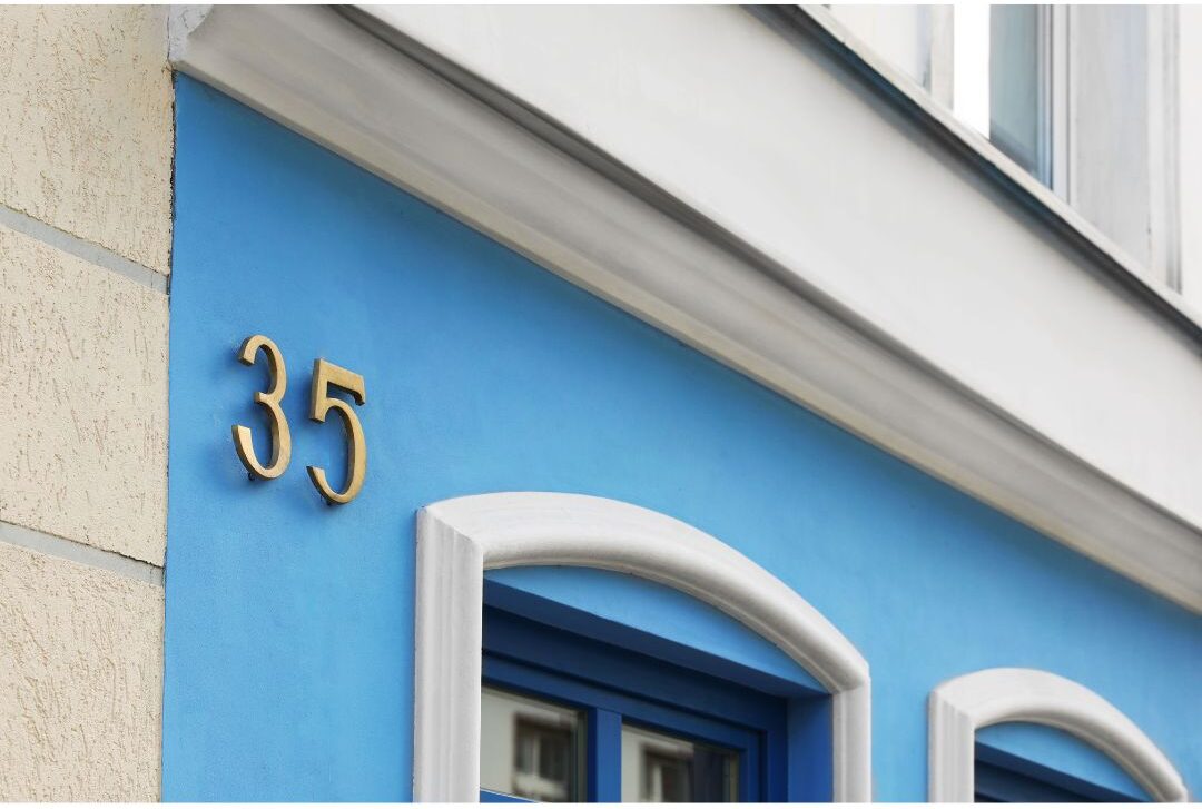 modern floating black house numbers mounted on light wood paneling