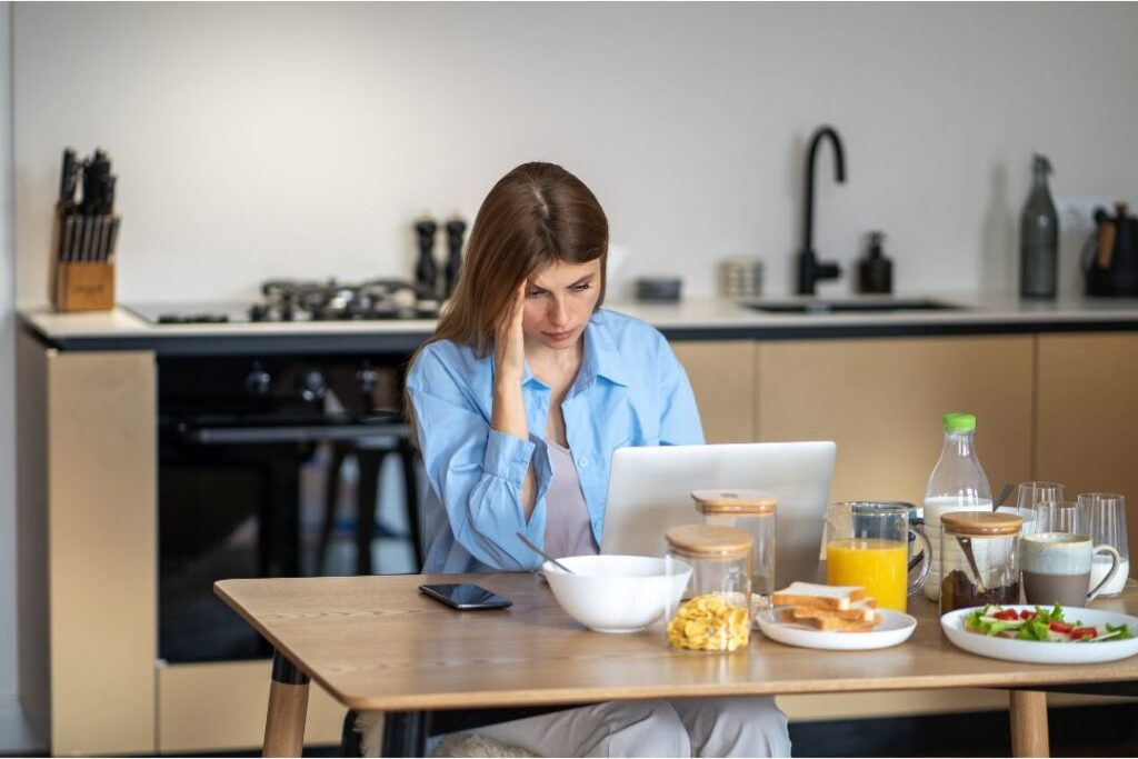thoughtful mother sitting at laptop reviewing bills illustrating money habits that keep families broke