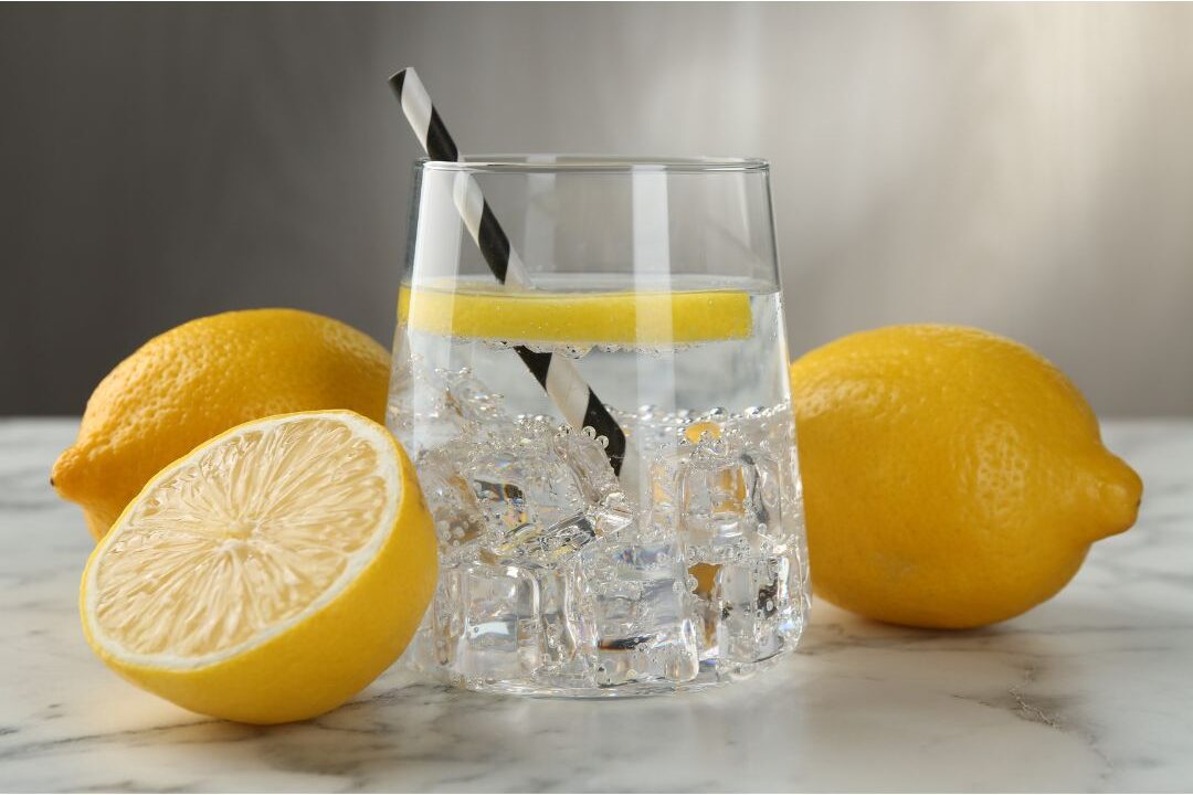 clear glass of water with fresh lemon slice on marble counter highlighting 45 daily habits that make life easier