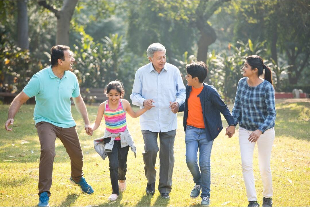 multi generational family standing together outdoor in sunlit field