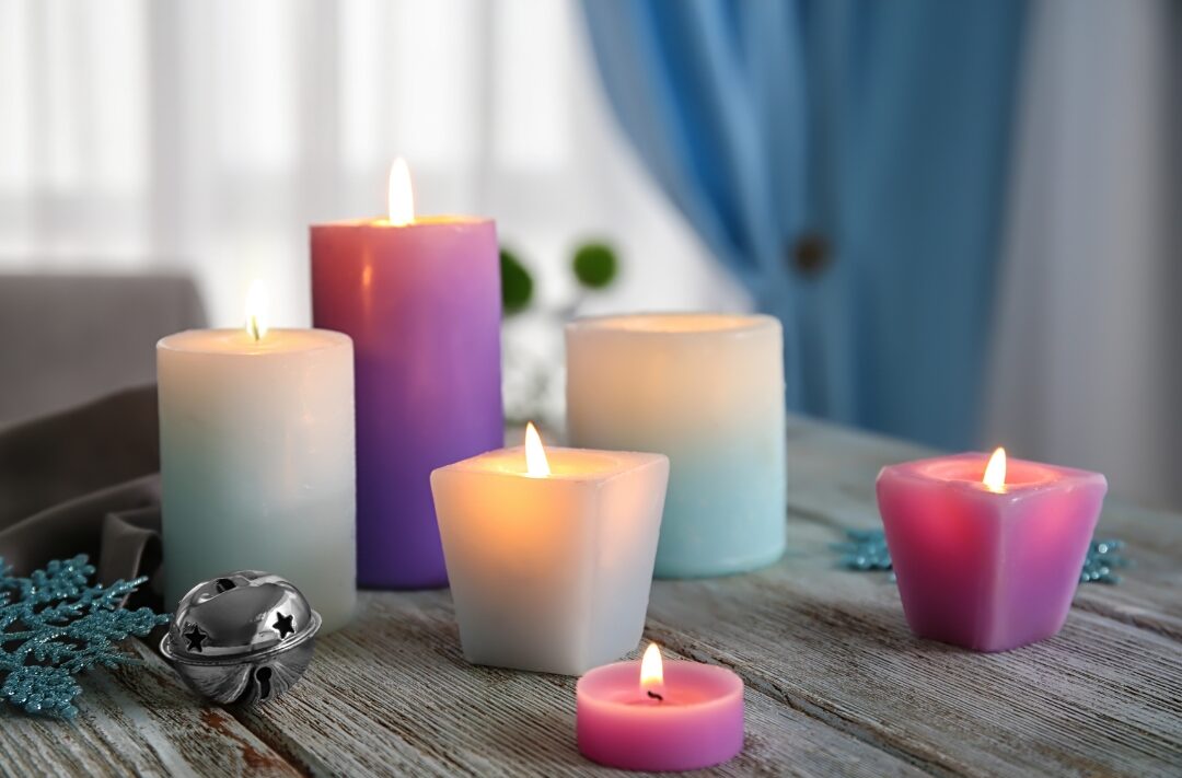 warm beeswax taper candle glowing gently on wooden table