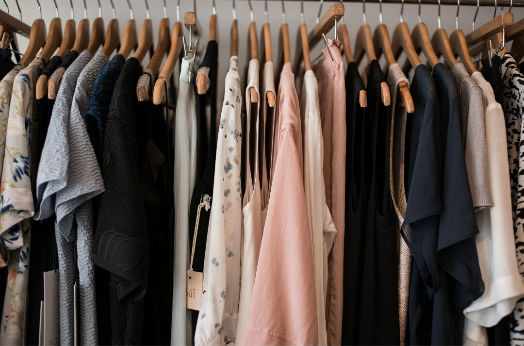 neatly organized closet hanging rack with matching wooden hangers listing 101 things to declutter this weekend