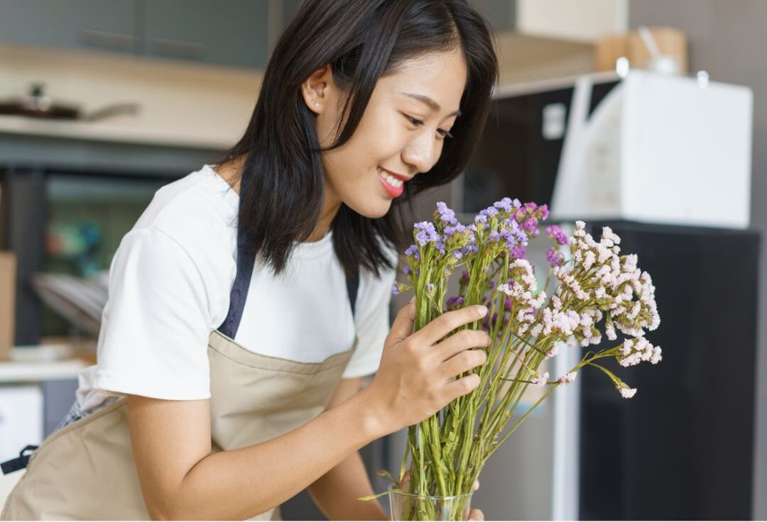 home assistant arranging fresh flowers on clean kitchen island