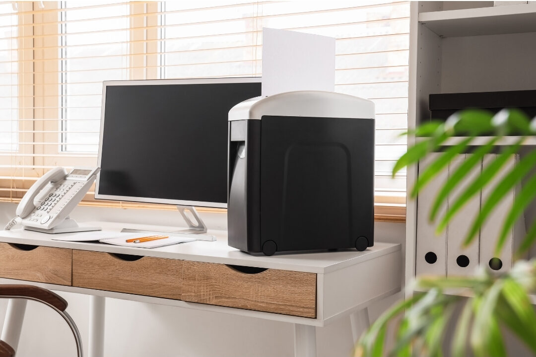 clean paper shredder sitting neatly beside a tidy home office desk