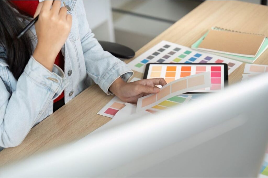 "woman reviewing colorful calendar and tablet on dining table
