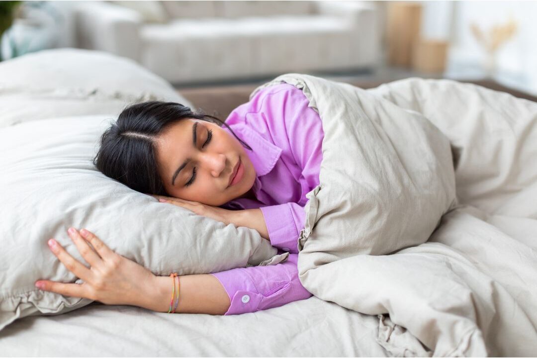 woman lying peacefully in bed under soft white linen duvet
