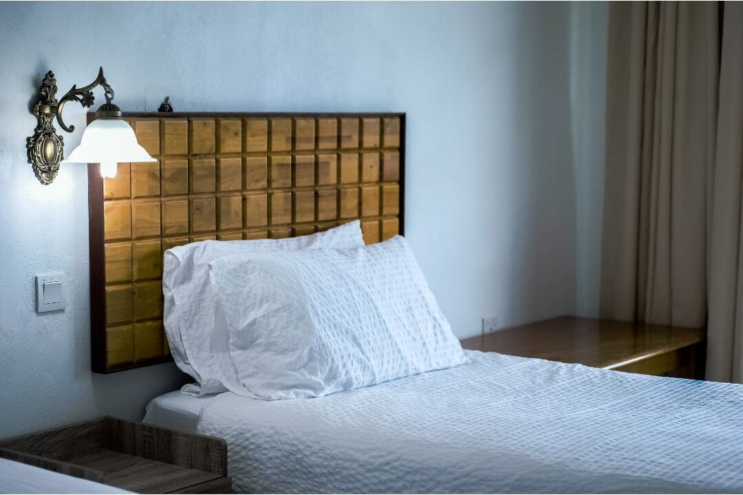 pair of plug-in brass sconce lights mounted beside bed headboard featuring 70 budget-friendly home upgrades that are actually worth it