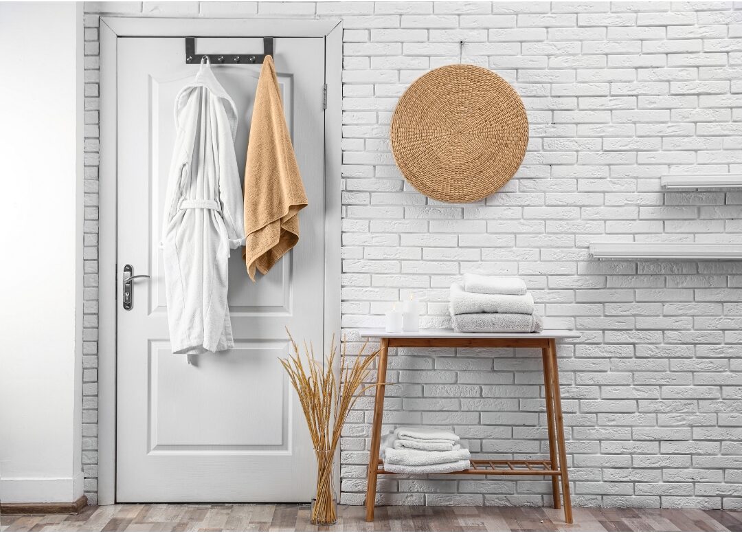 fluffy white cotton bathrobe hanging on brass door hook exploring 30 tiny luxuries every woman deserves
